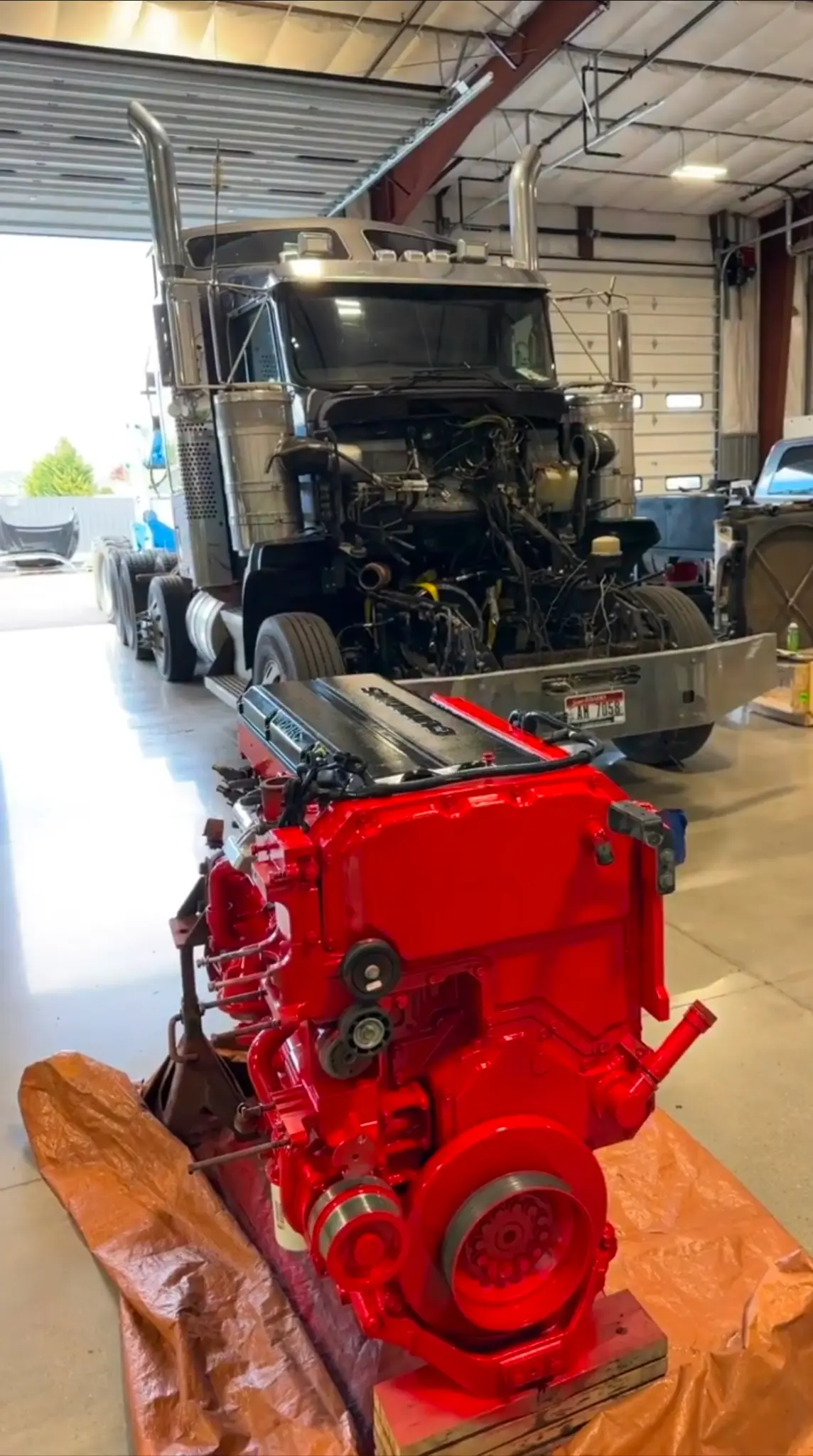 Fresh red diesel engine positioned in front of a semi truck for installation